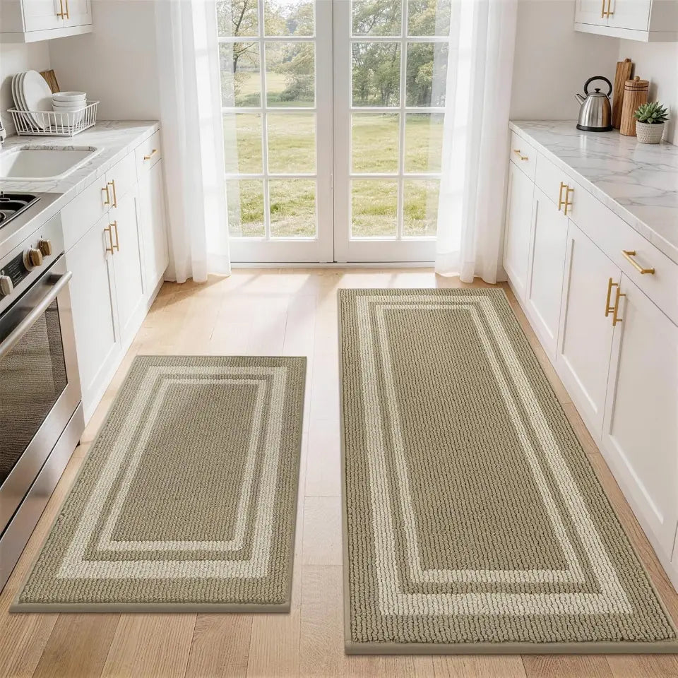 Two beige white frame kitchen rugs on a wooden floor with a view of a garden through a window.