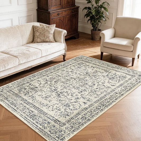 Faded grey & cream patterned neutral textured area rug on a wooden floor with a sofa and chair in a living room setting.