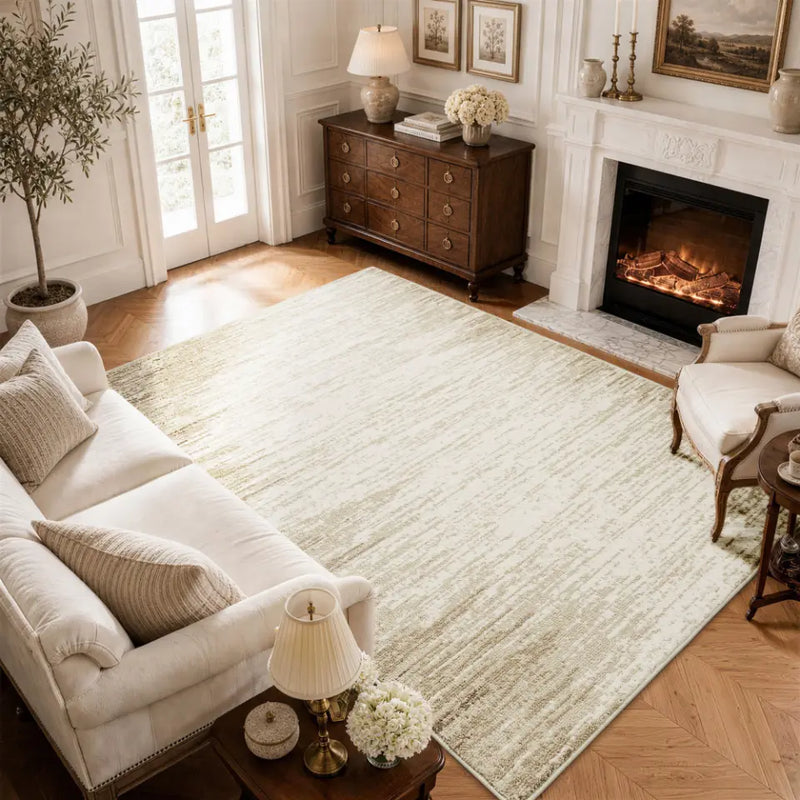 Living room with a large taupe & cream rug, sofa, armchair, and fireplace.