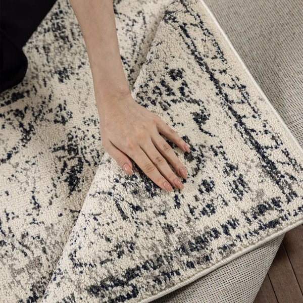 Close-up of a textured area rug with a pattern on a wooden floor.