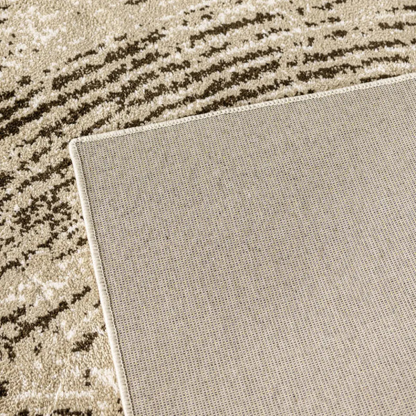 Close-up of a textured rug corner with a neutral color palette on a wooden floor.