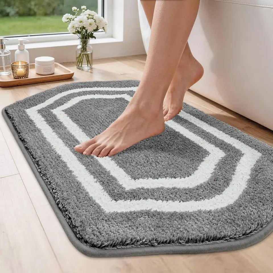 Person stepping onto a grey bath mat with geometric pattern in a bathroom setting.