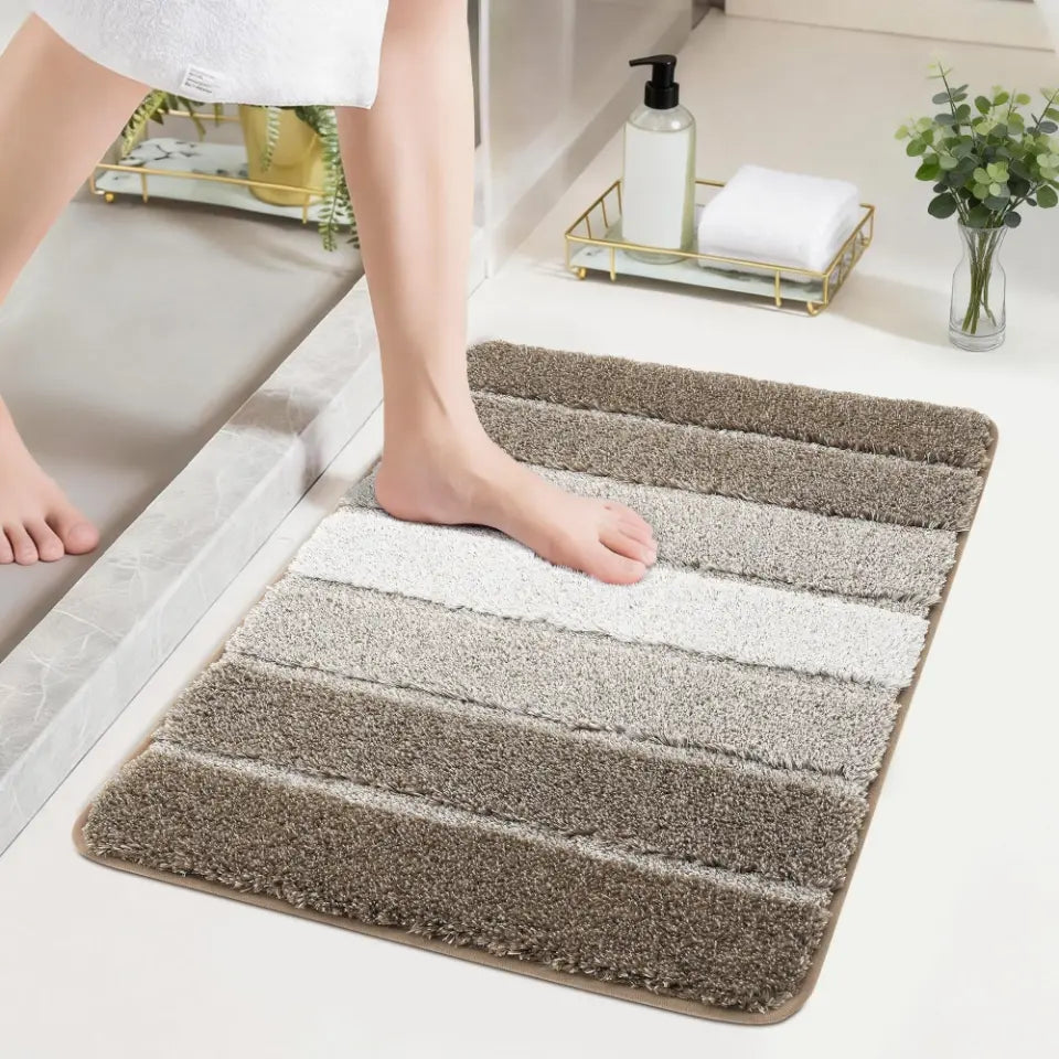Brown striped bath mat on a bathroom floor with a person stepping onto it.