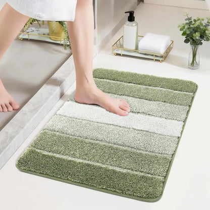 Green and white striped bath mat with a foot stepping onto it, in a bathroom setting.