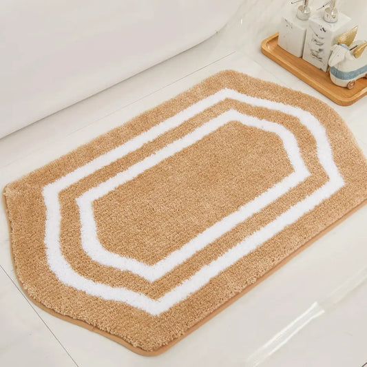 Beige bath mat with white border on a bathroom floor