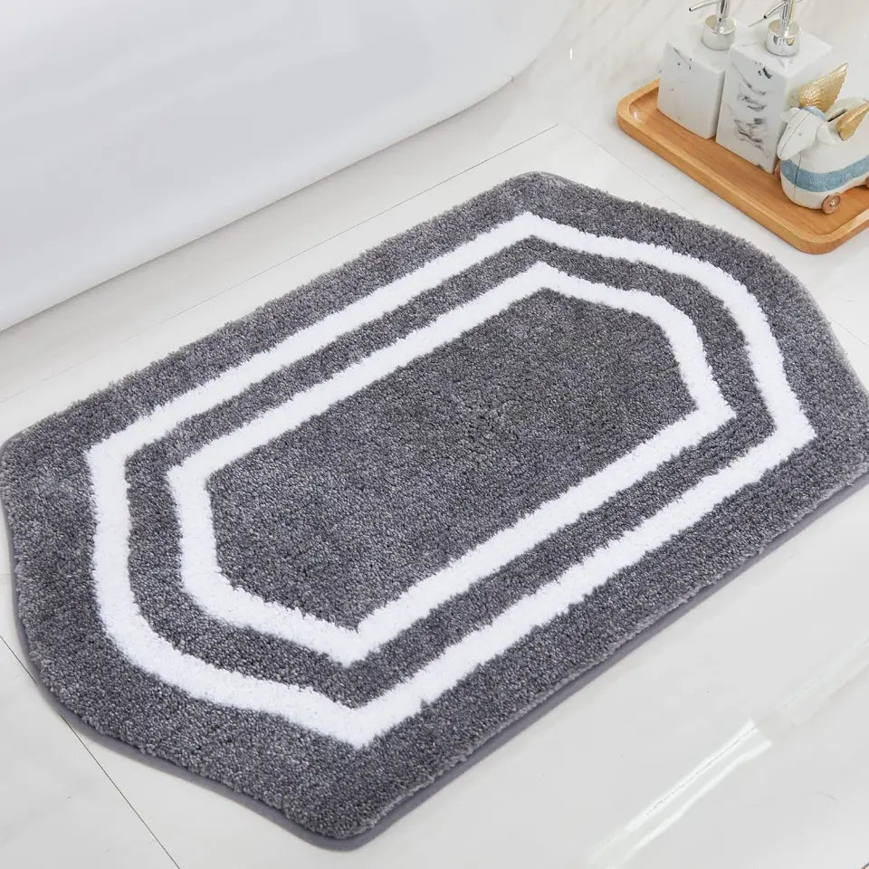 Grey bath mat with white border on a bathroom floor