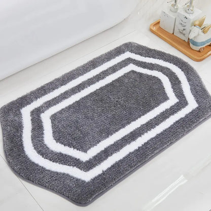 Grey bath mat with white border on a bathroom floor