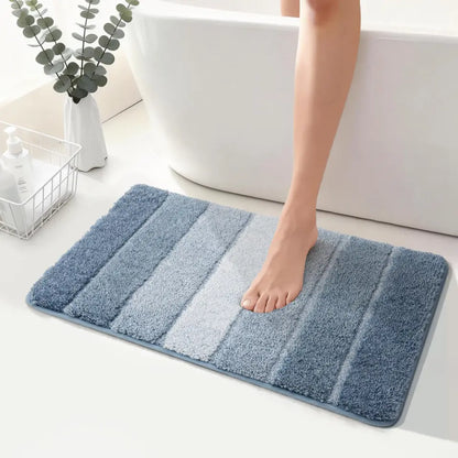 Blue striped bath mat on a bathroom floor with a foot stepping onto it.