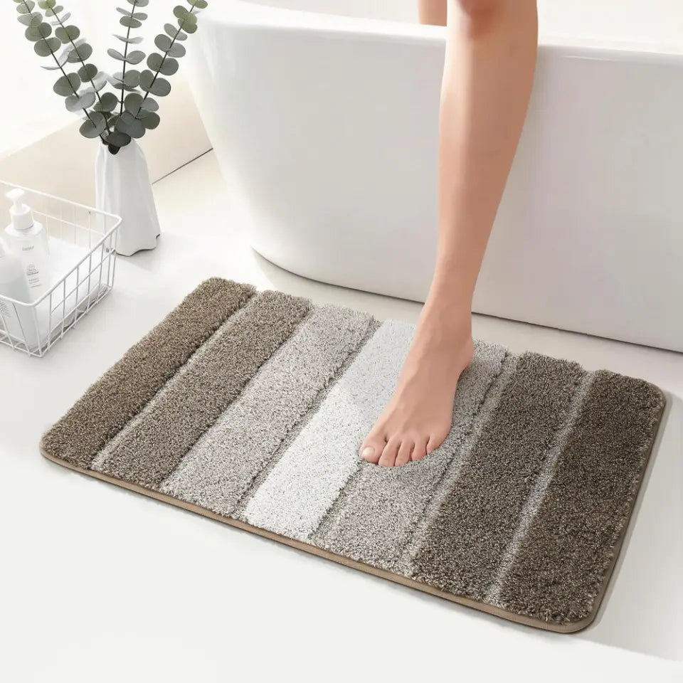 Brown bathroom mat with striped pattern on a bathroom floor, person stepping onto it.