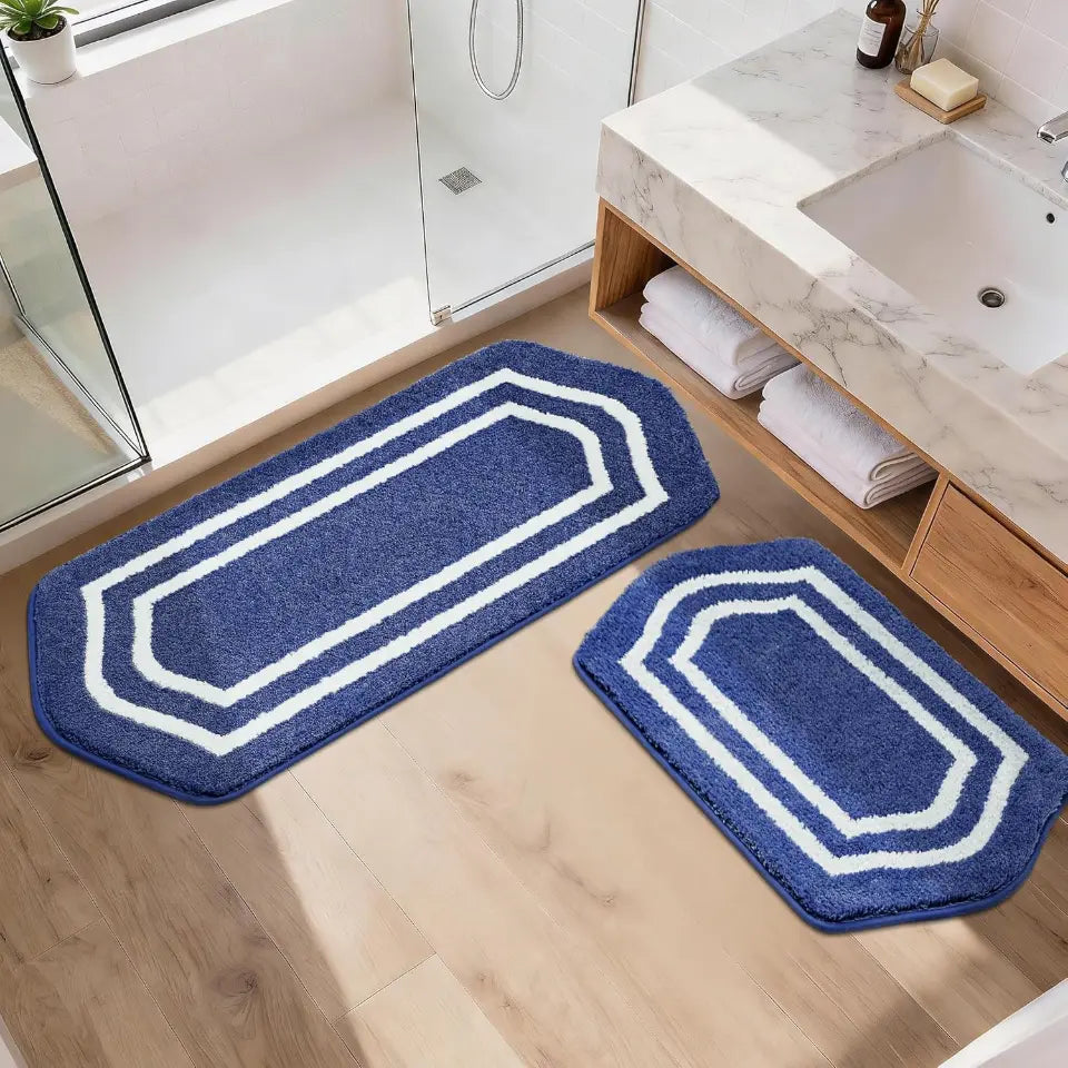 Set of two blue bath mats with white borders on a bathroom floor.