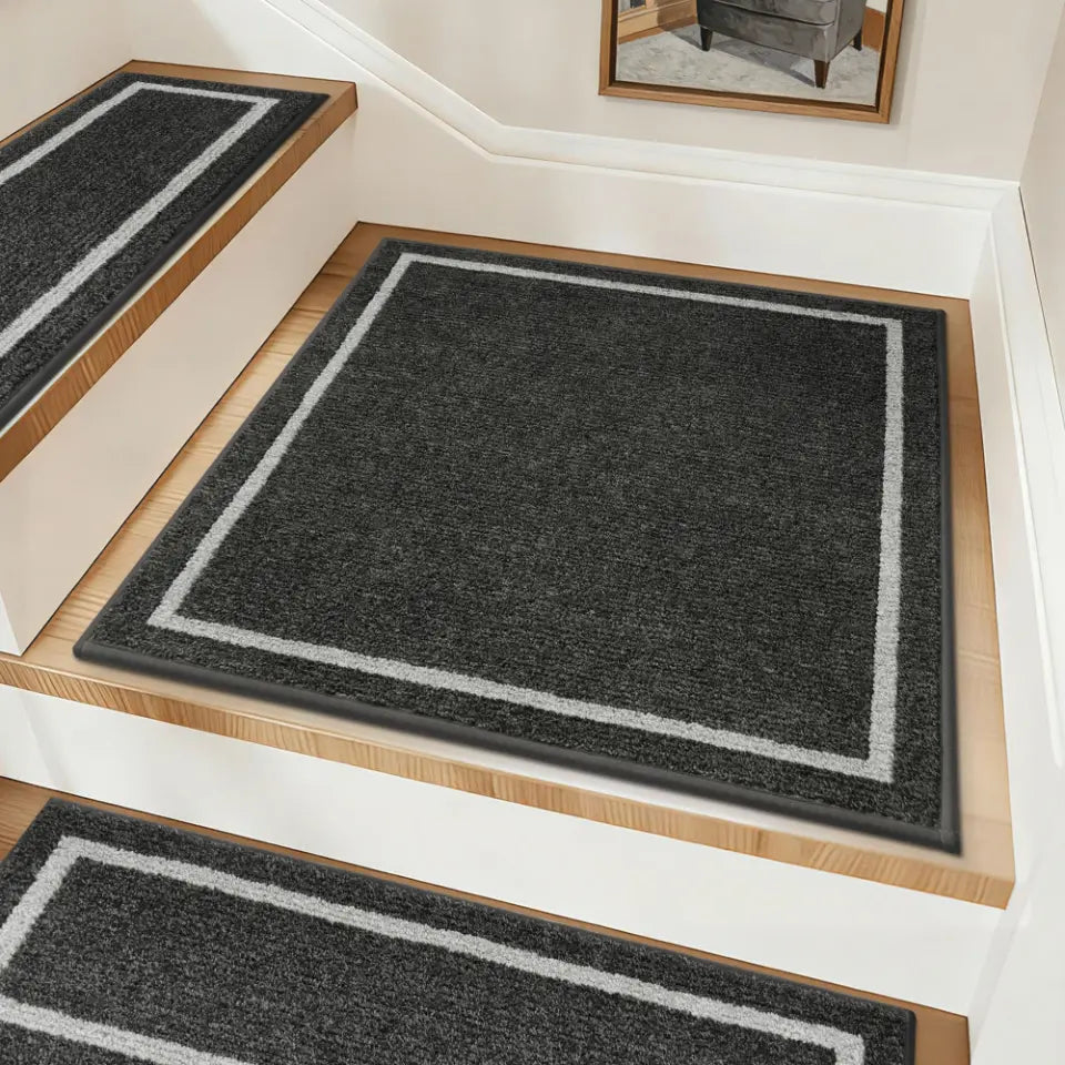 Set of black stair mats with white borders on a wooden staircase.