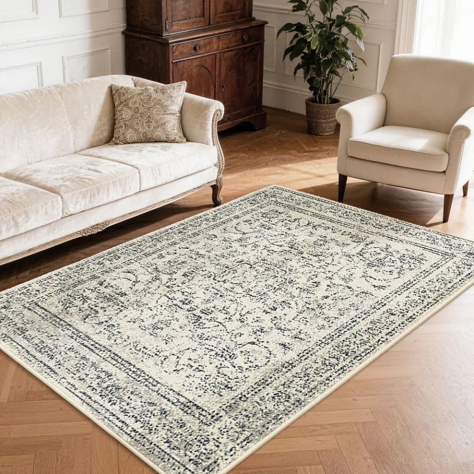 Faded grey & cream patterned neutral textured area rug on a wooden floor with a sofa and chair in a living room setting.