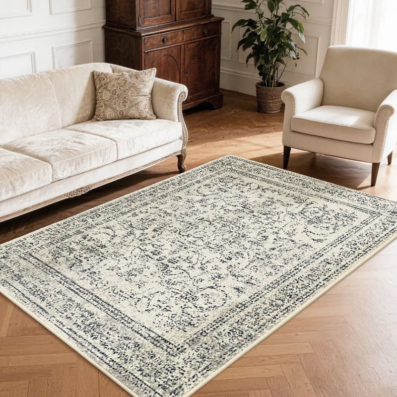 Faded grey & cream patterned neutral textured area rug on a wooden floor with a sofa and chair in a living room setting.