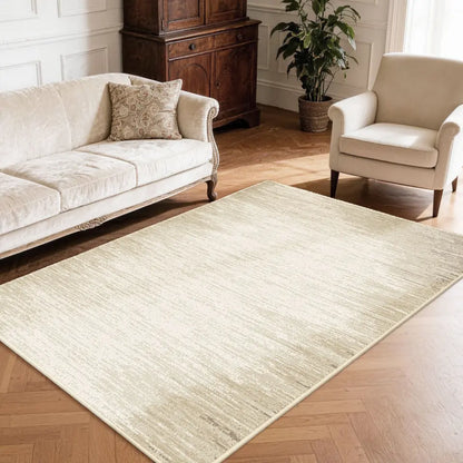 Living room with a large taupe & cream gradient area rug, white sofa, and armchair.