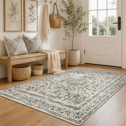 Nestled entryway with a faded grey & cream patterned rug, bench, and coat rack.