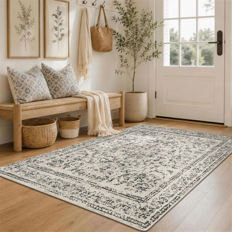 Nestled entryway with a faded grey & cream patterned rug, bench, and coat rack.