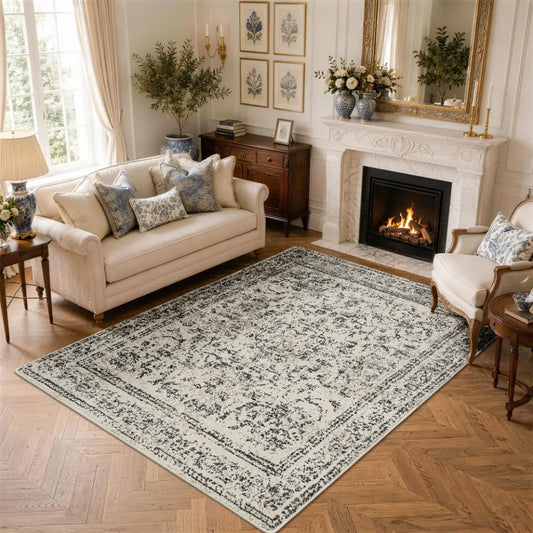 Faded grey & cream patterned neutral textured area rug on a wooden floor with a sofa and chair in a living room setting.