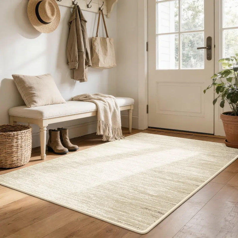 Nestled entryway with a bench, taupe & cream rug, and door.