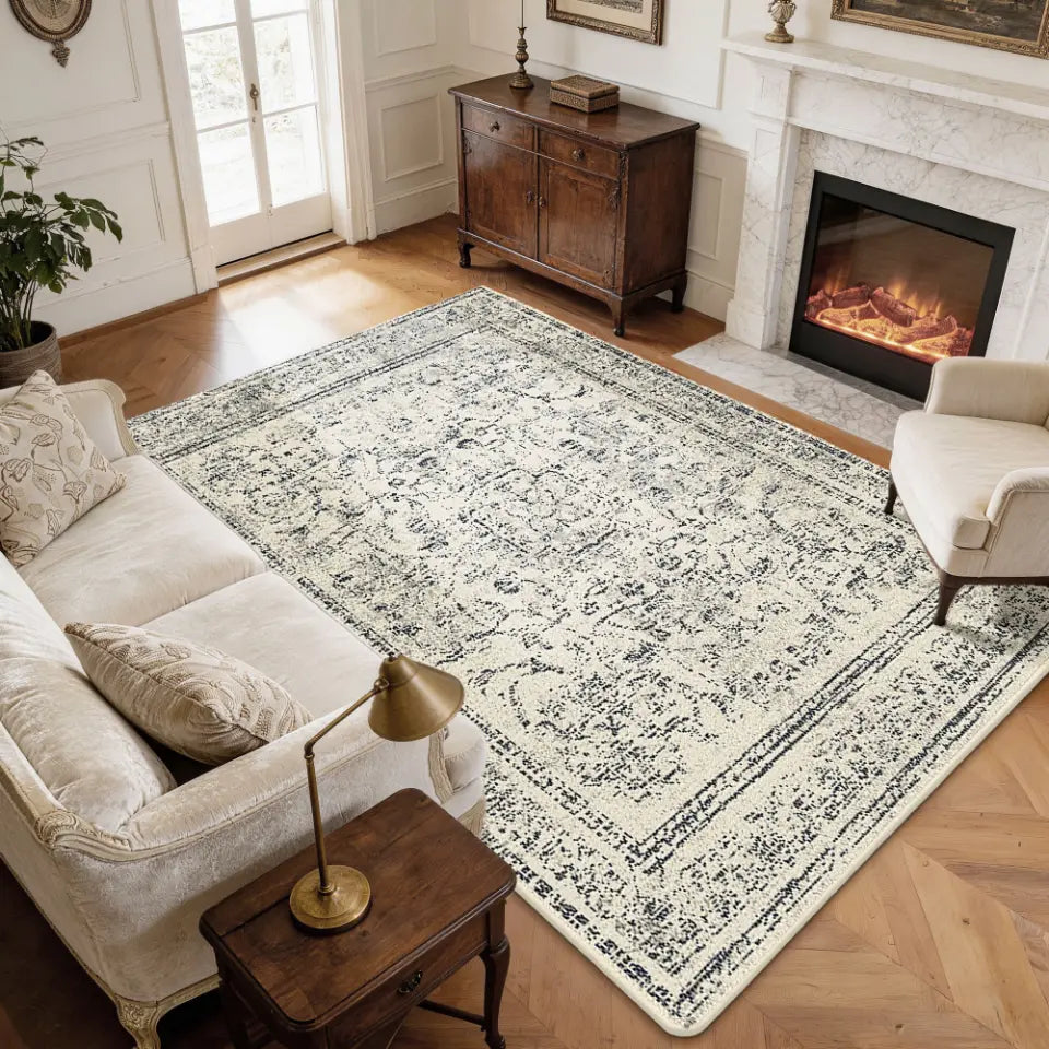 Living room with a patterned faded grey & cream rug, sofa, and fireplace.