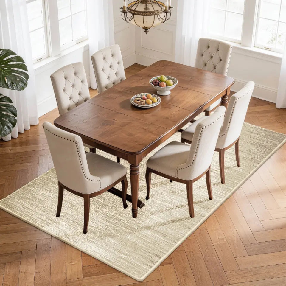 Dining room with wooden table and upholstered chairs on a taupe & cream area rug