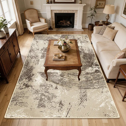 Living room with a large oatmeal & espresso patterned rug, wooden coffee table, and beige sofa.