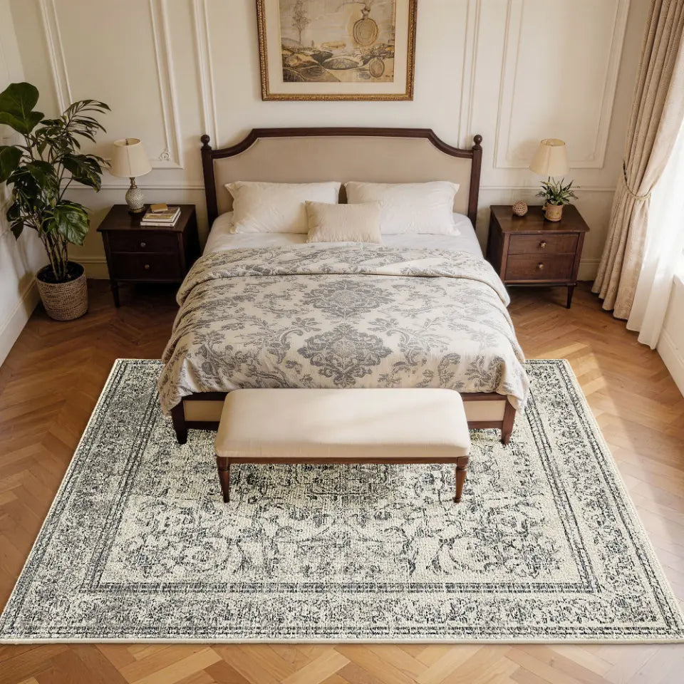 Bedroom with a large bed, patterned faded grey & cream rug, and wooden nightstands.