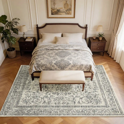Bedroom with a large bed, patterned faded grey & cream rug, and wooden nightstands.