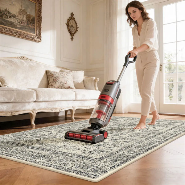 Woman using a vacuum cleaner on a area rug in a living room.