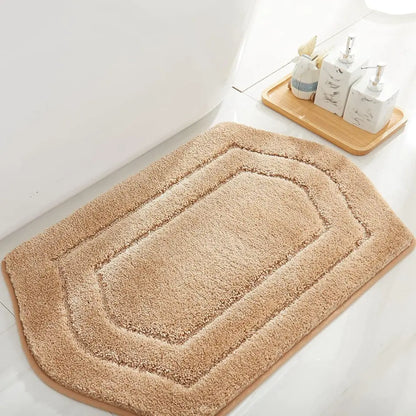 Beige bath mat on a bathroom floor with a wooden tray and toiletries in the background.