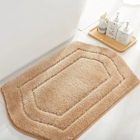 Beige bath mat on a bathroom floor with a wooden tray and toiletries in the background.
