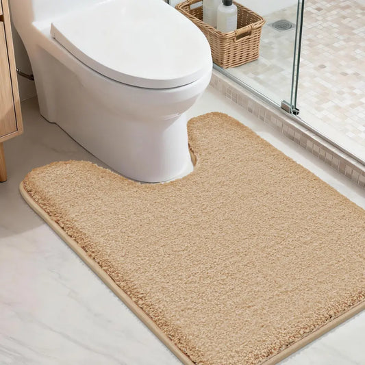 Beige u shaped toilet rug in front of a toilet in a bathroom setting