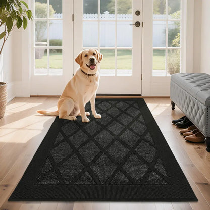 Dog sitting on a black doormat in a home setting with a door and bench in the background.