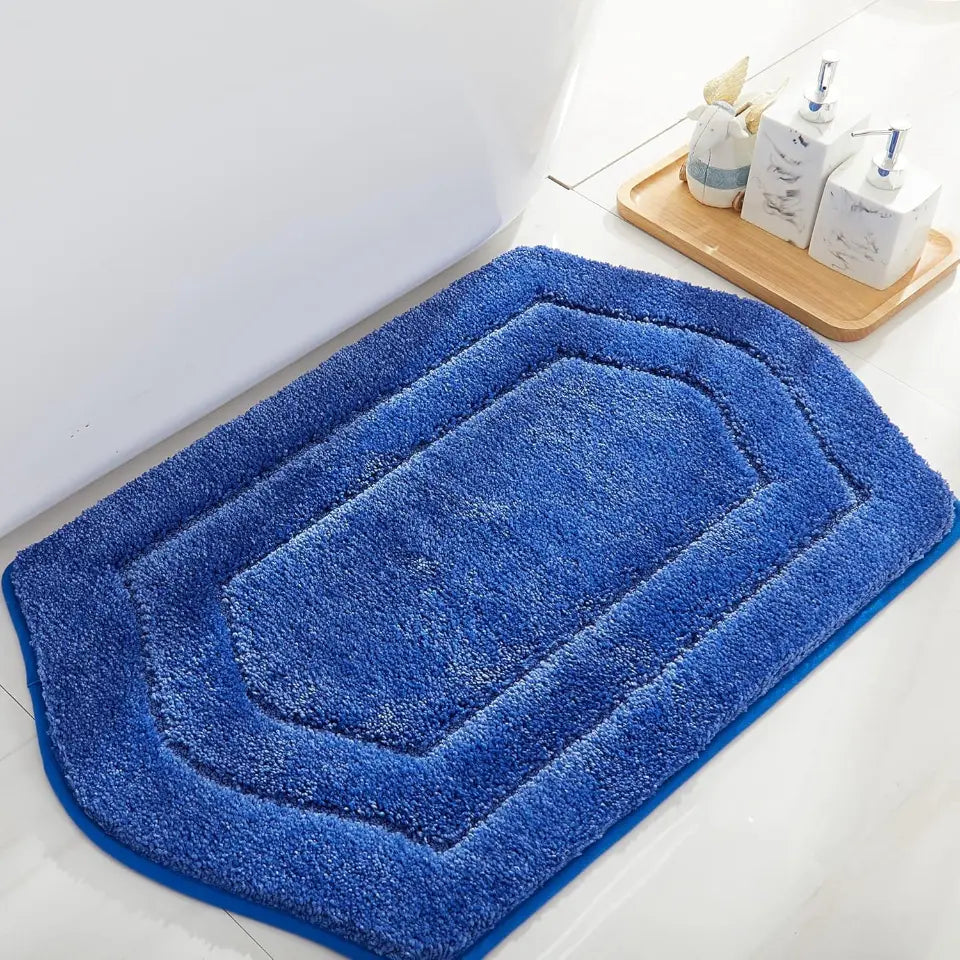 Blue bath mat on a bathroom floor with toiletries in the background