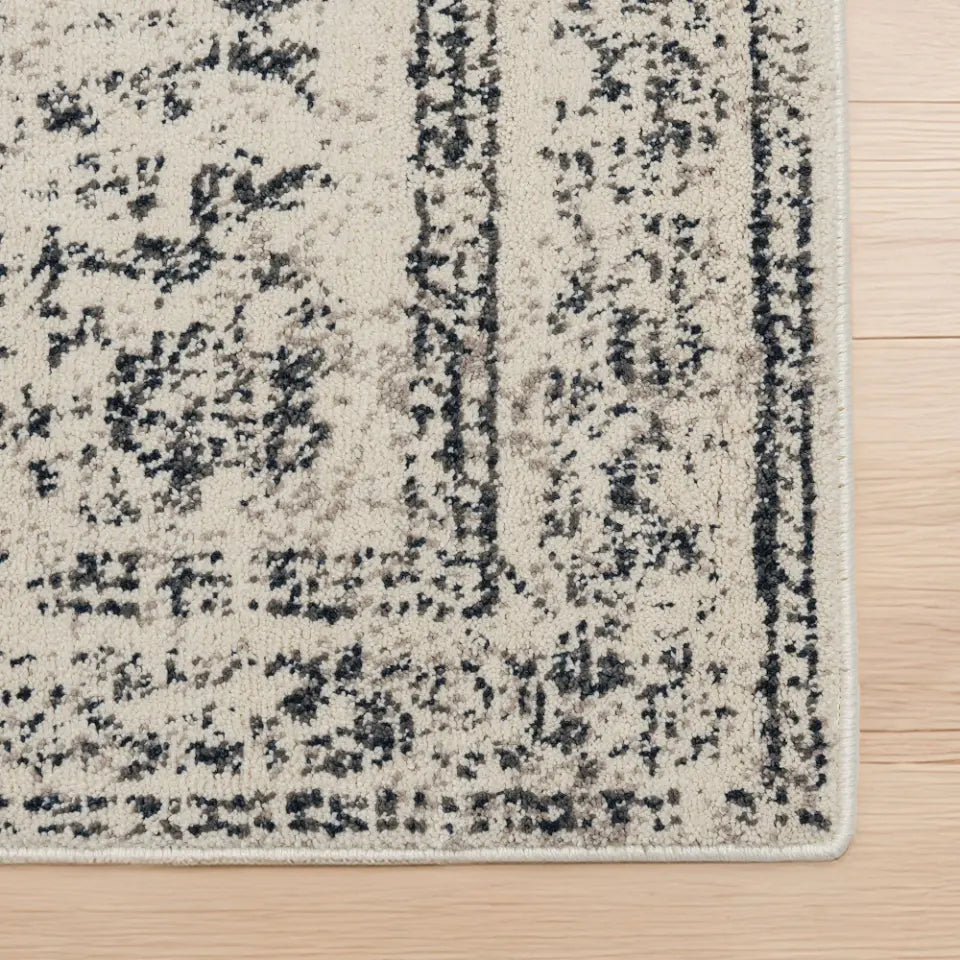 Close-up of a textured area rug with a pattern on a wooden floor.