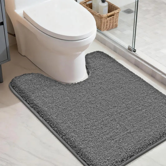 Dark grey u rug in front of a toilet in a bathroom setting
