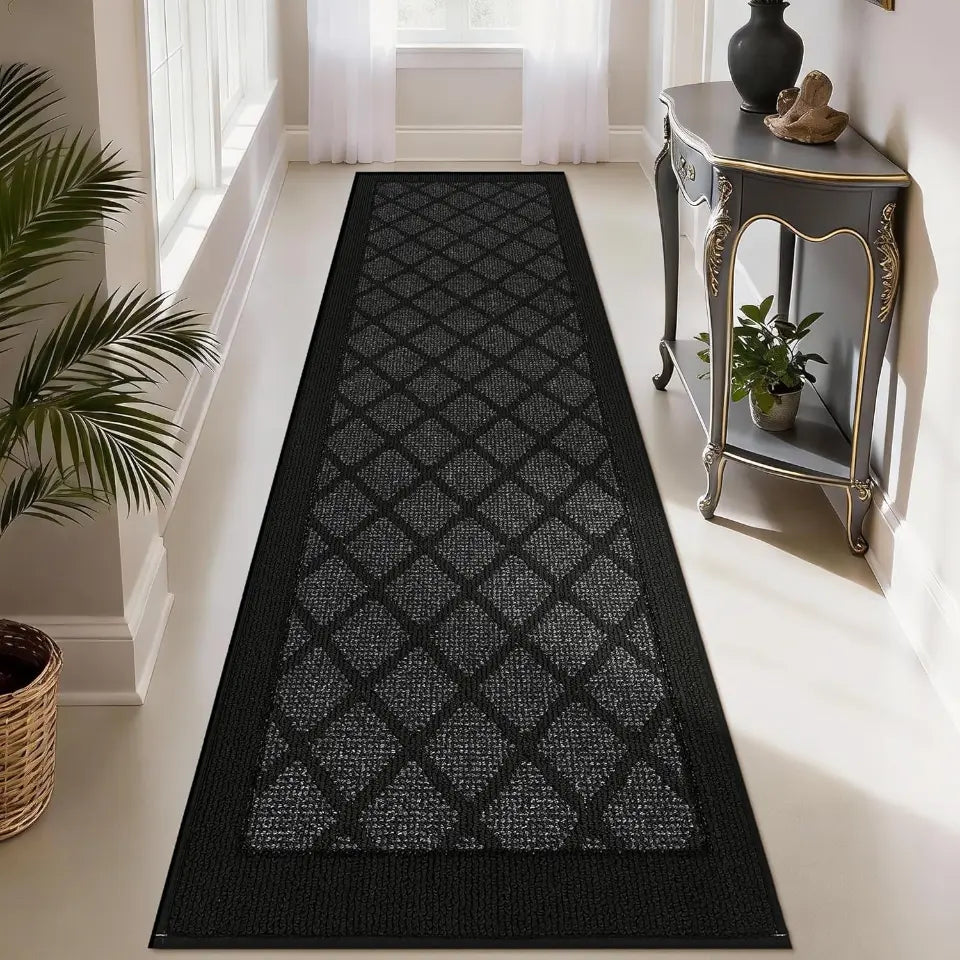 Dark grey patterned rug on a light wooden floor with a side table and plants in the background.