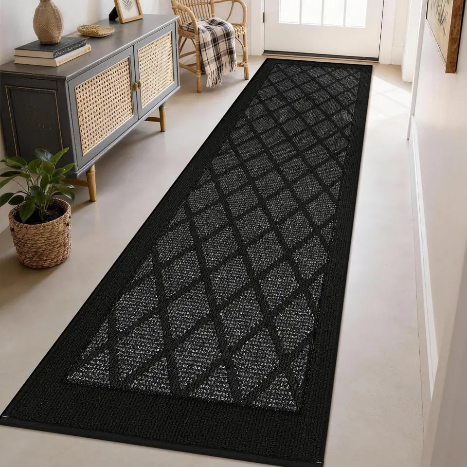 Dark grey geometric patterned rug on a light wooden floor in a room with furniture.