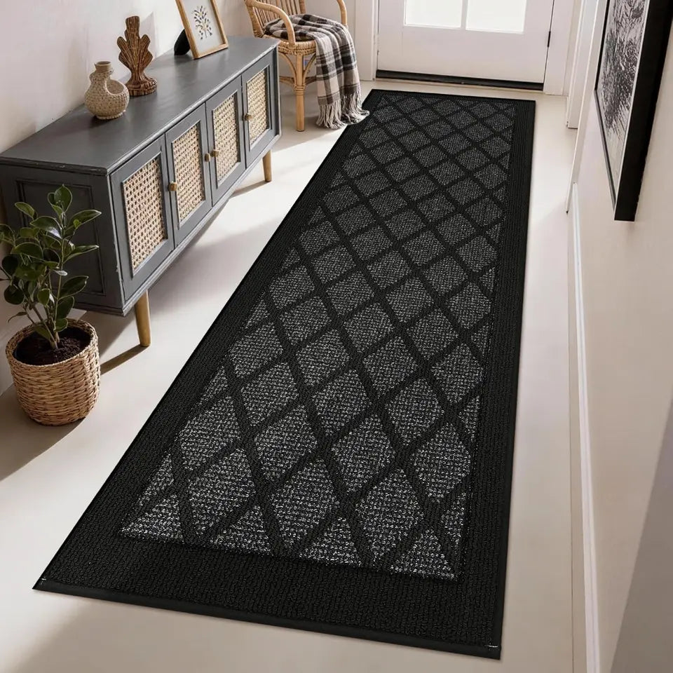 Dark grey geometric patterned rug on a white floor in a room with a cabinet and plant.
