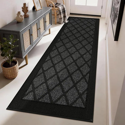 Dark grey geometric patterned rug on a white floor in a room with a cabinet and plant.