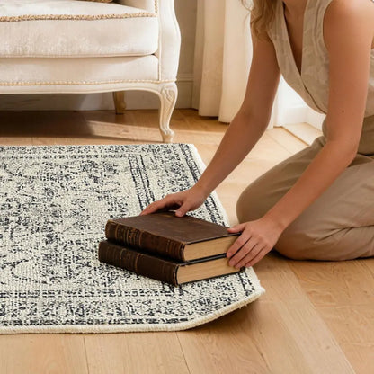 Person arranging books on a patterned rug to flatten the corner of rug