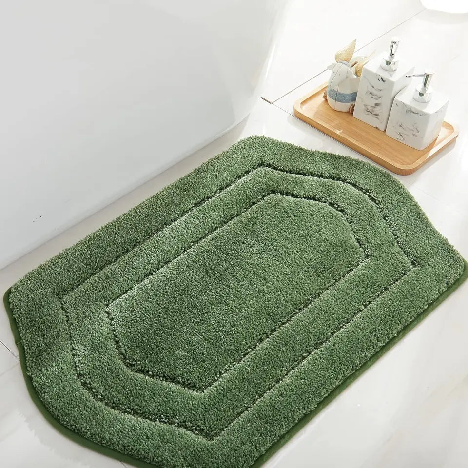 Green bath mat on a bathroom floor with toiletries on a tray.
