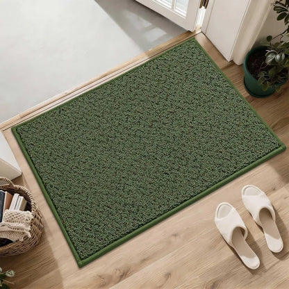 Green doormat on a wooden floor with white slippers and a plant in the background