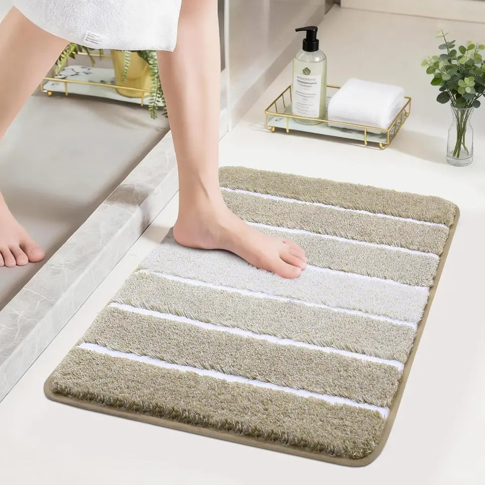Person stepping onto a beige High Contrast striped bath mat in a bathroom setting.