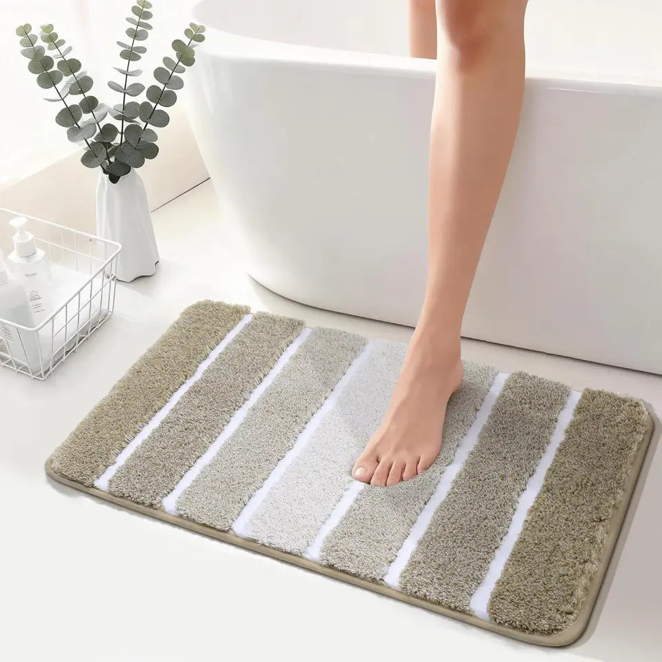 Person stepping onto a beige High Contrast striped bath mat in a bathroom setting