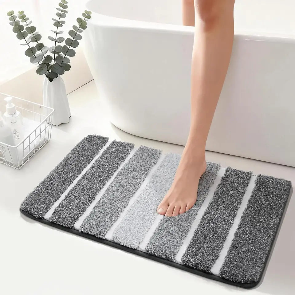 High Contrast grey striped bath mat with a foot stepping onto it in a bathroom setting.
