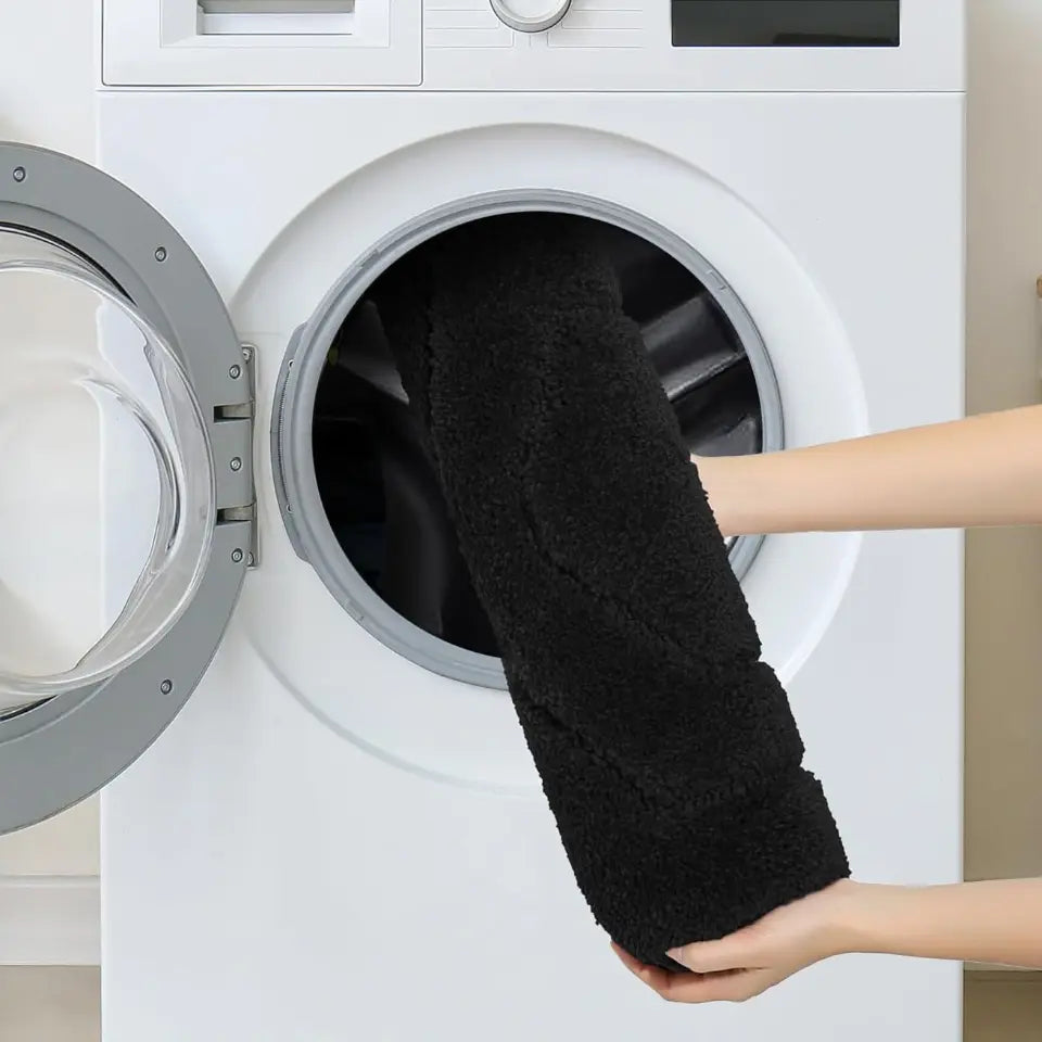 Person using a bath fluffy bath rug to clean inside a white washing machine.