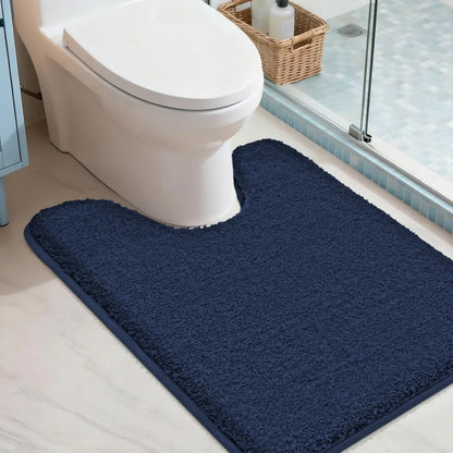 Navy blue U shaped bath mat in front of a toilet in a bathroom setting.