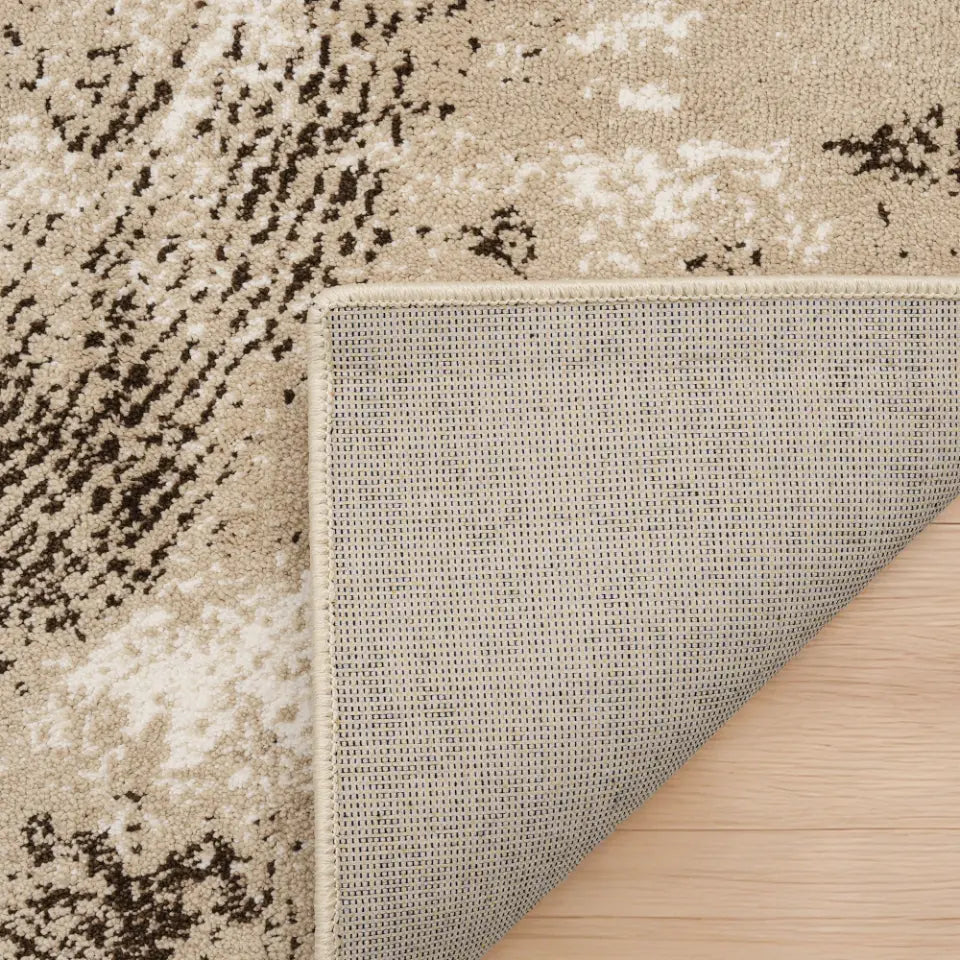 Close-up of a textured rug corner with a neutral color palette on a wooden floor.