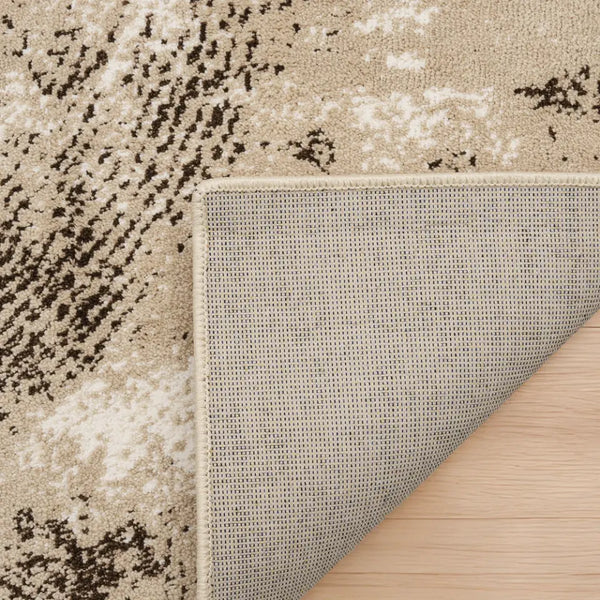 Close-up of a textured rug corner with a neutral color palette on a wooden floor.