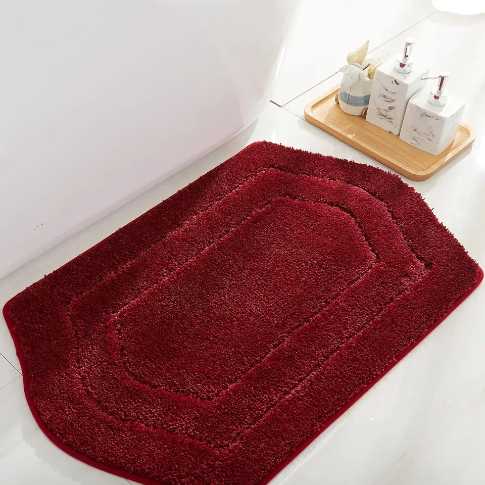 Red bath mat on a bathroom floor with toiletries in the background